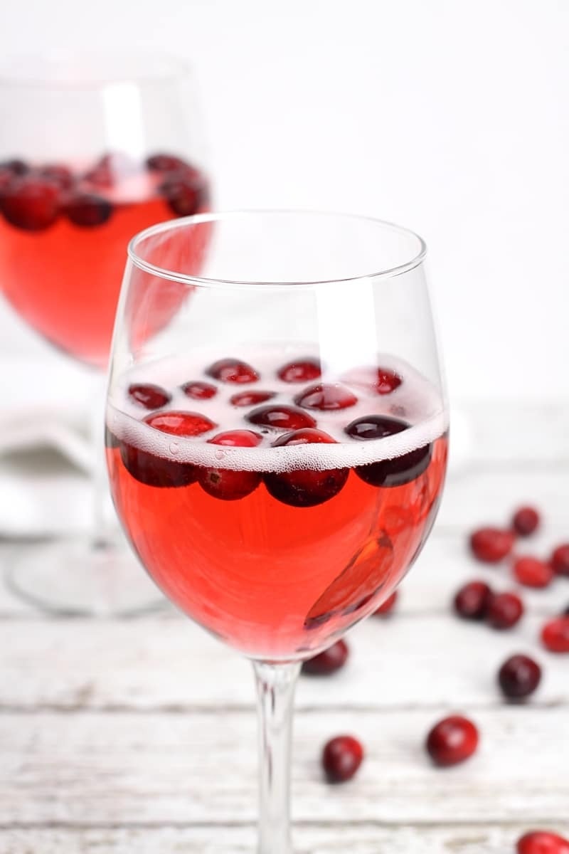Cranberry prosecco punch in  wine glass garnished with fresh cranberries. 