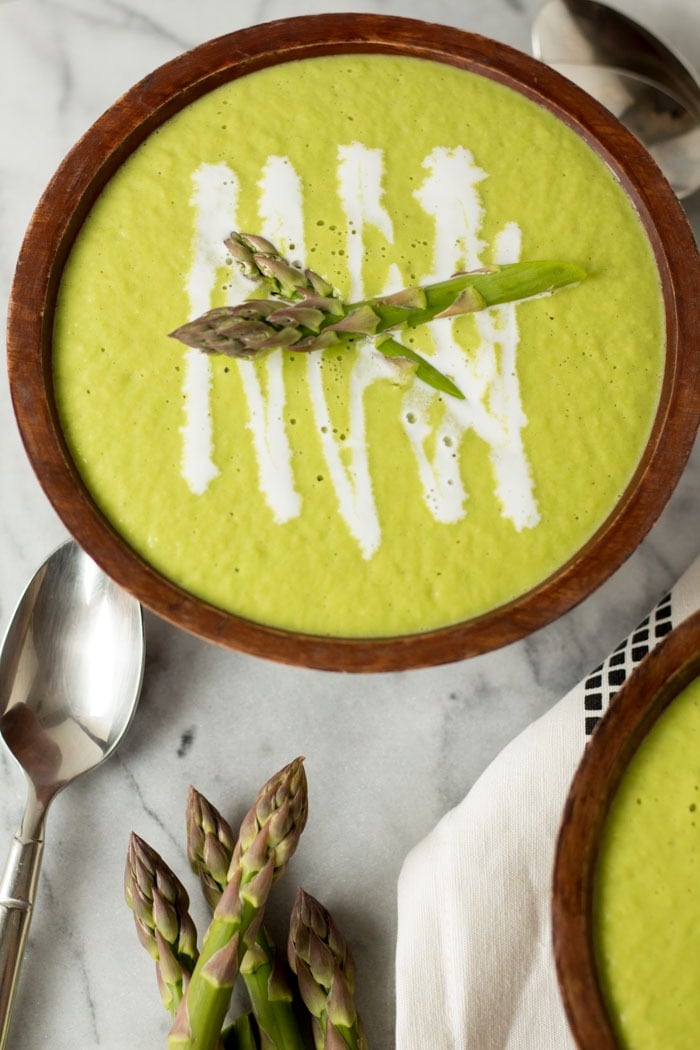 Bowls of homemade Creamy Asparagus and Leek Soup with coconut milk and asparagus on top