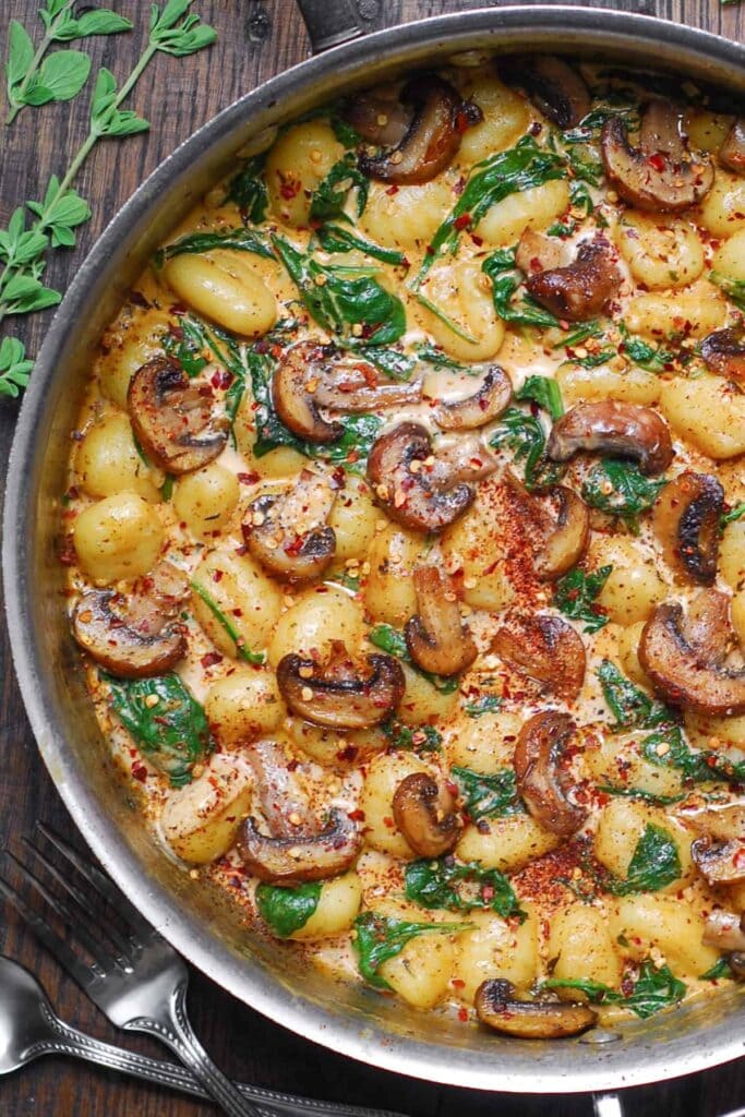 Creamy spinach and mushroom gnocchi on a pan. 