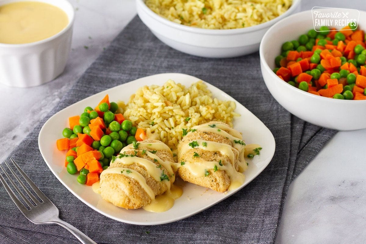 Two Crescent Chicken Roll-Ups on a plate with fried rice and mix carrots and green peas
