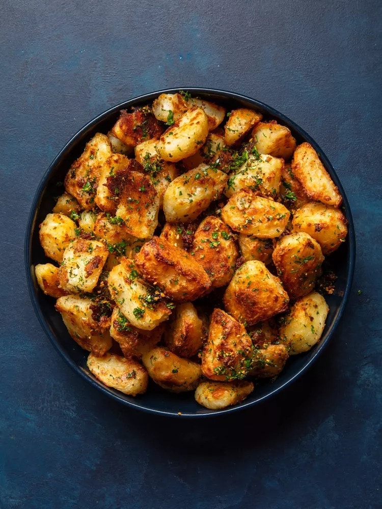 Roasted potatoes in a bowl with fresh herbs. 