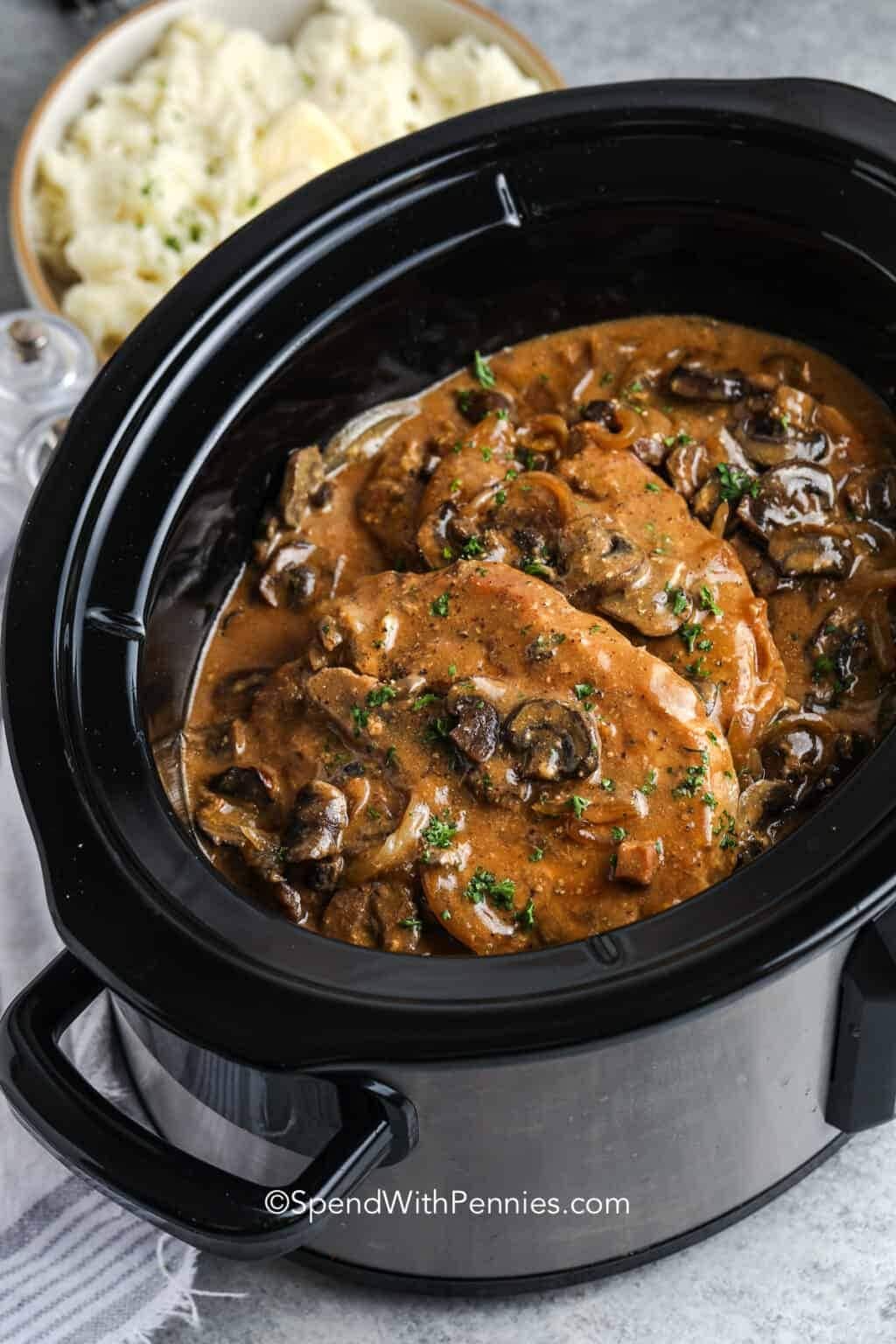 Pork chop cooked in a slow cooker with gravy and mushroom. 