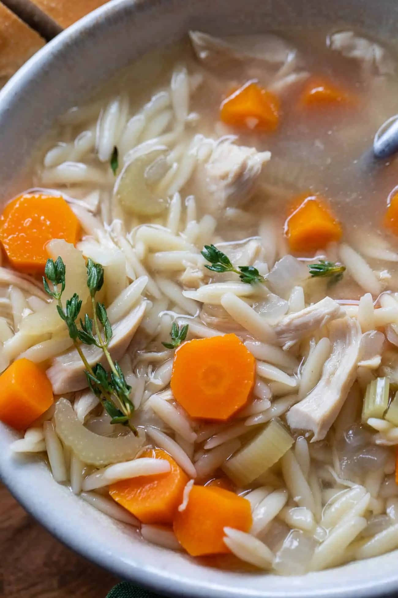 Closeup of chicken orzo soup in a white bowl. 