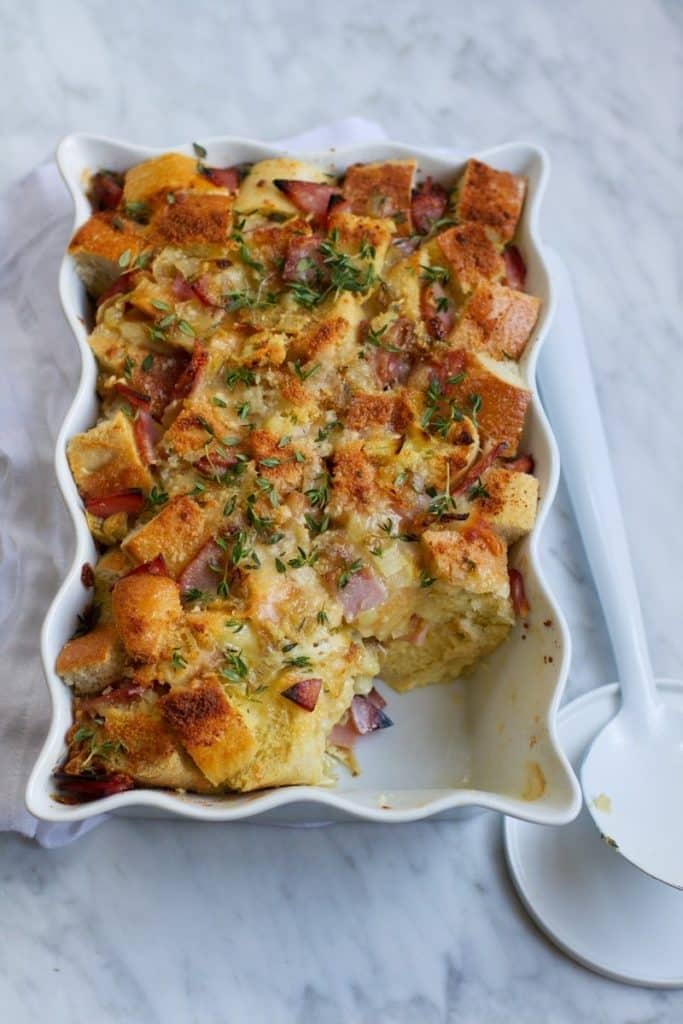 Croque monsieur savory bread pudding on  a white baking dish. 