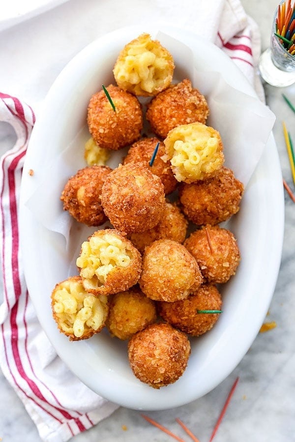 Breaded mac and cheese balls with stick served on a plate.
