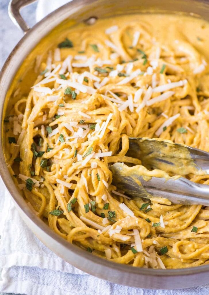 Pasta with pumpkin sauce garnished with cheese and herbs. 