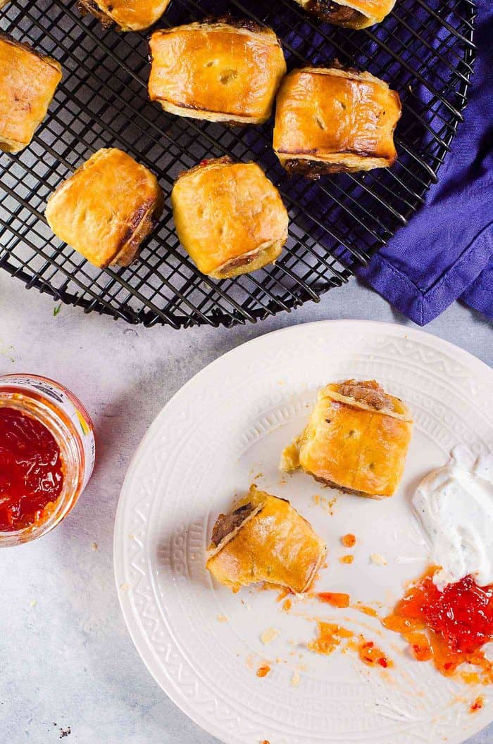 Appetizing sausage rolls with sauce on a cooling rack