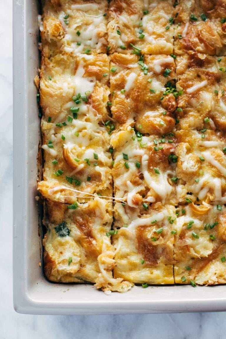 Egg and Croissant Brunch Bake slices into squares on a casserole and garnished with spring onions 