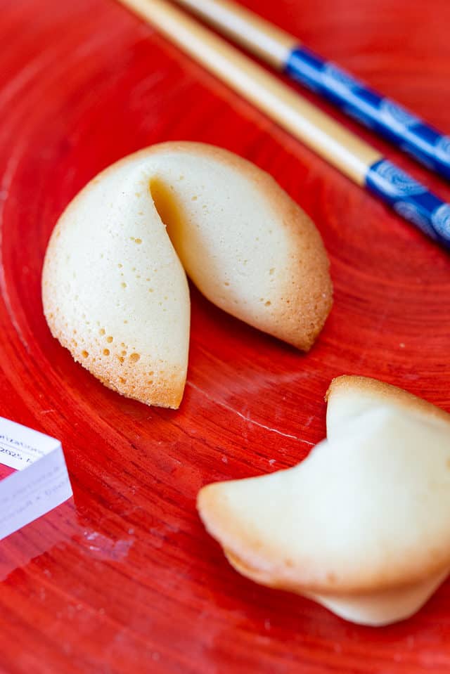 Chinese fortune cookies on a red plate with chopsticks. A traditional treat with hidden messages