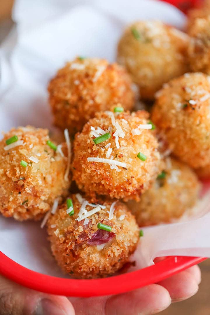 Bunch of fried mashed potato balls on a red plate. 