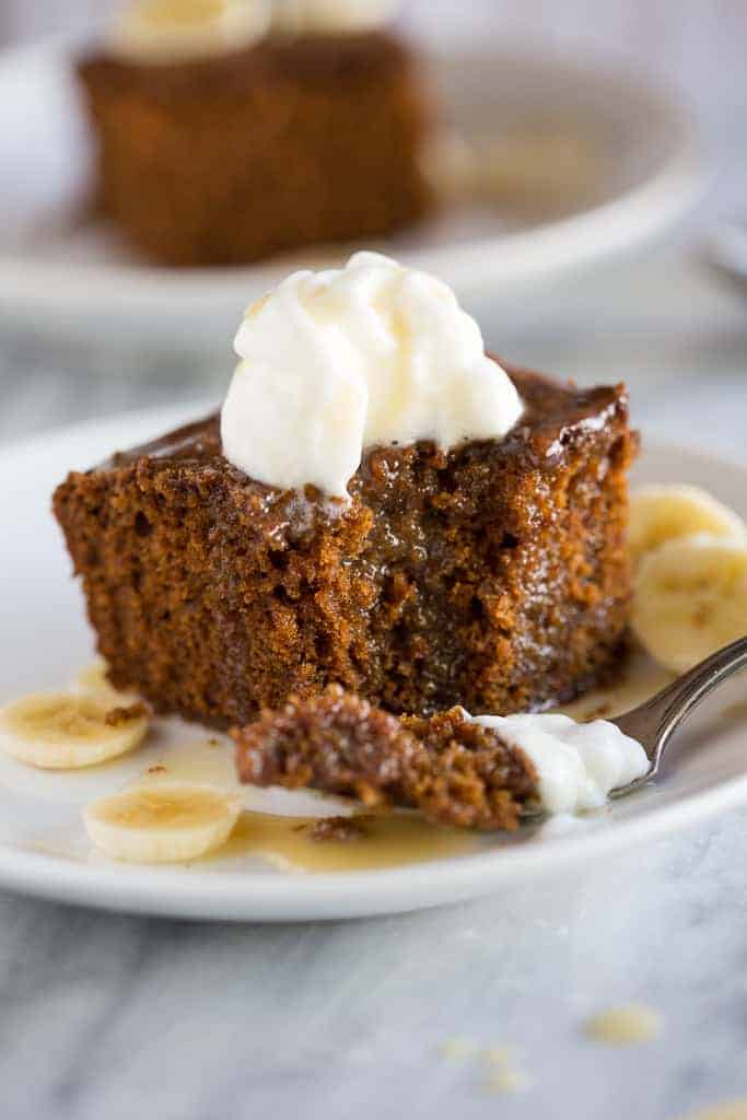 A slice of gingerbread cake topped with whipped cream and fresh bananas on a plate
