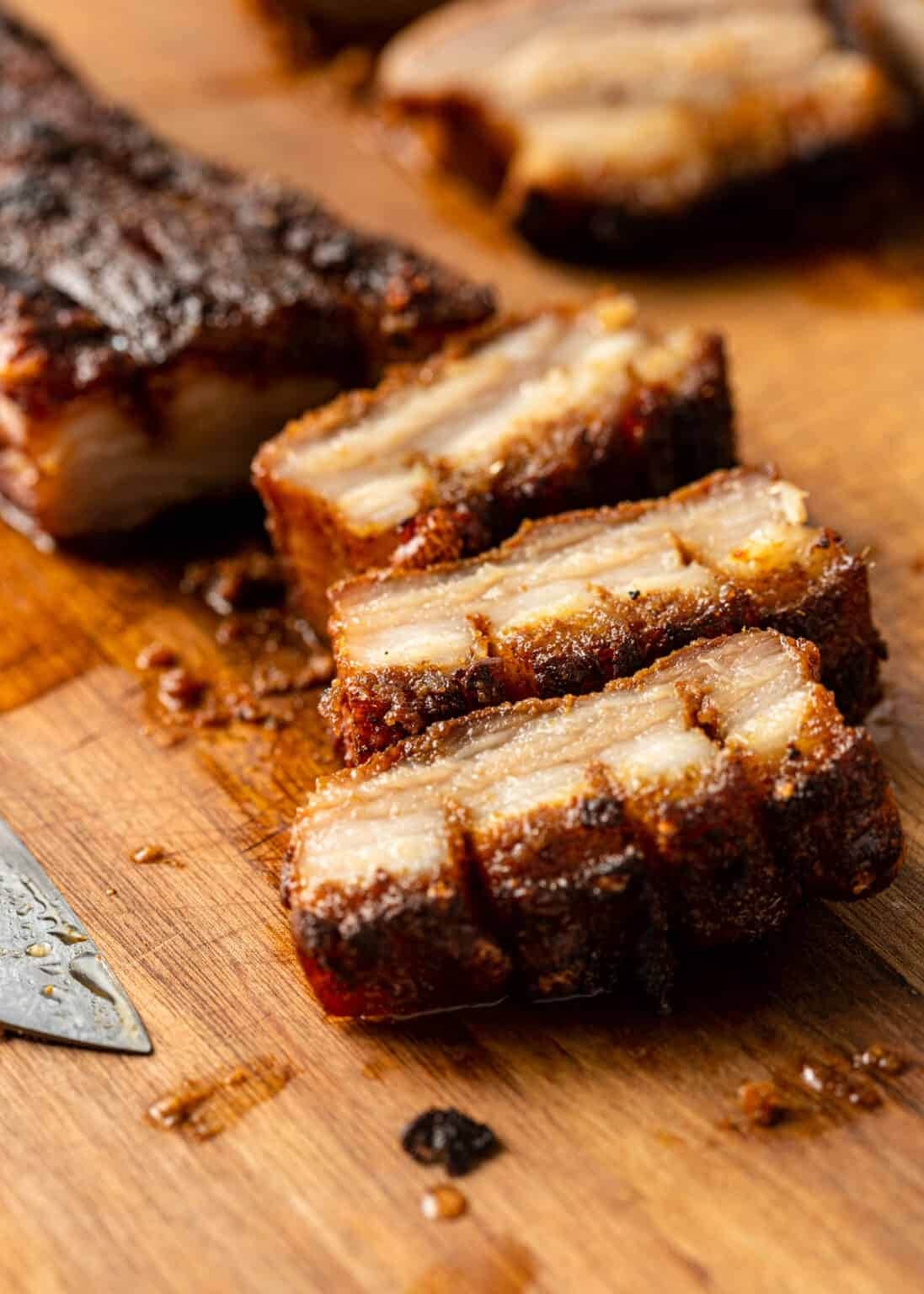 Glazed Honey Pork Belly chopped on a wooden chopping board