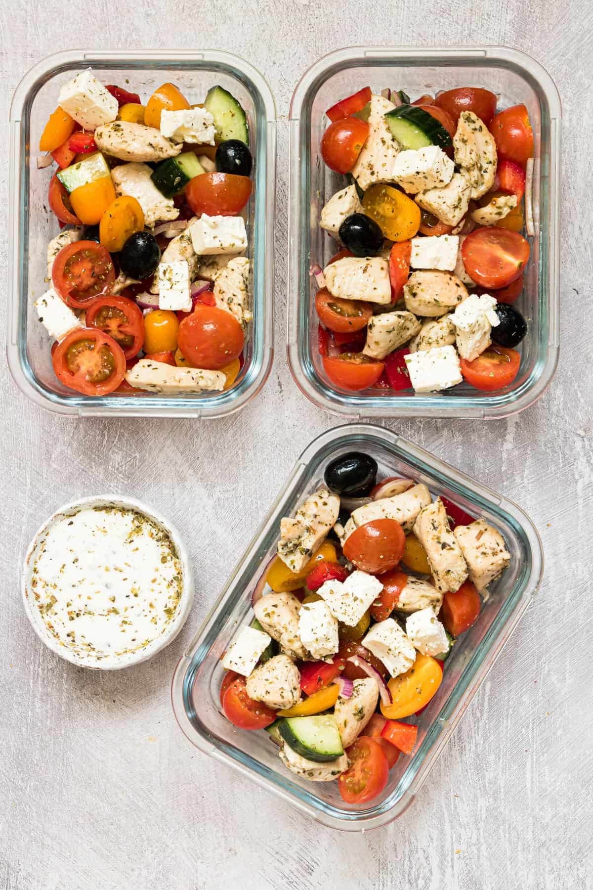 Greek chicken meal prep bowls made with fresh oregano, zesty lemon, juicy chicken chunks, creamy feta, and healthy vegetables.