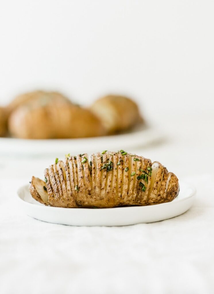Hasselback potatoes on a white plate. 