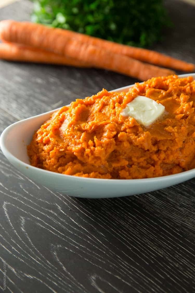 Mashed carrots topped with butter slice on a boat-shaped bowl.