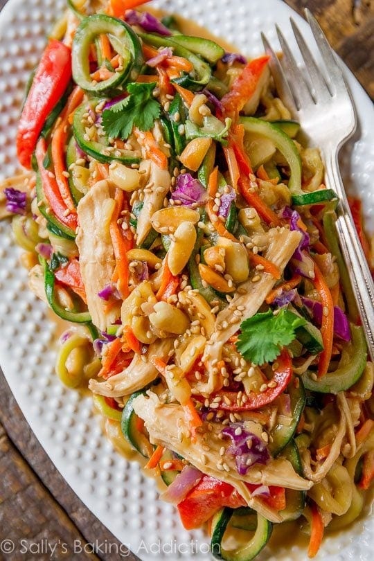 Serving of peanut chicken zucchini noodles with nuts, veggies and sesame seeds. 