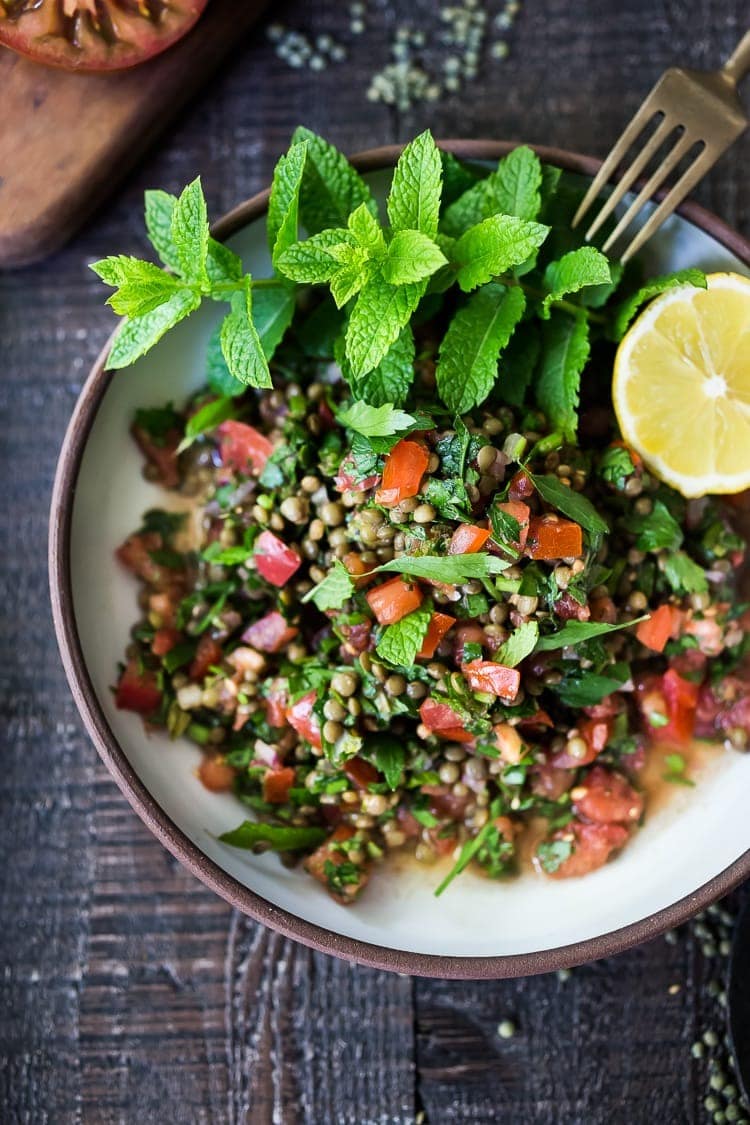 Lentil Tabouli salad on a plate with lentils, tomatoes, lemon, and herbs.