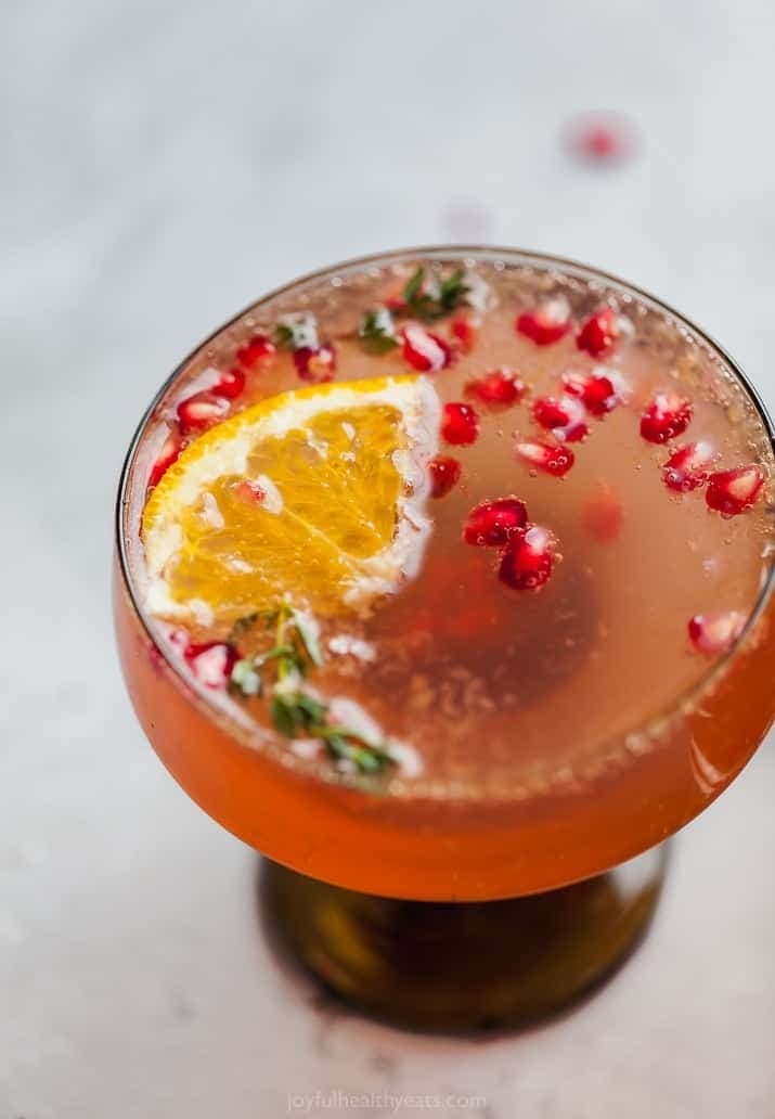 A cocktail with orange slices and pomegranate garnish.