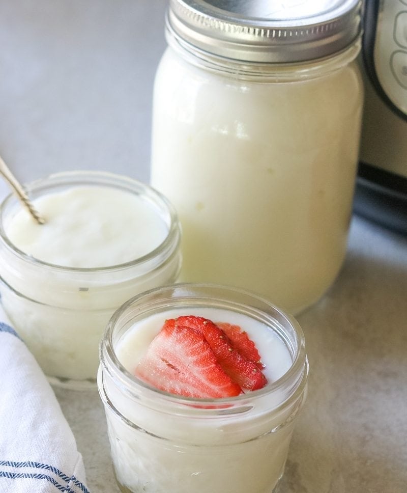 Instant pot yogurt in mason jars garnished with sliced strawberries. 