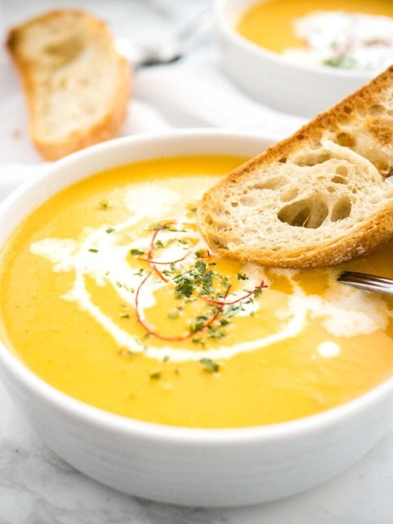 Bread dipped on a bowl of Instant Pot Carrot Soup