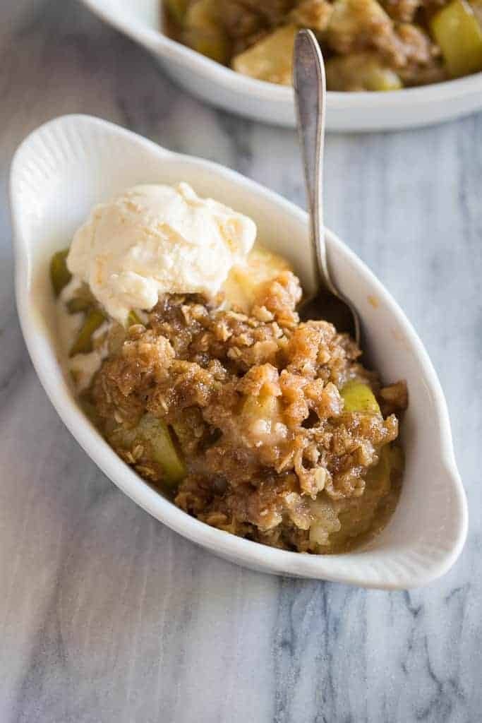 Apple crisp with vanilla ice cream on a bowl with spoon. 