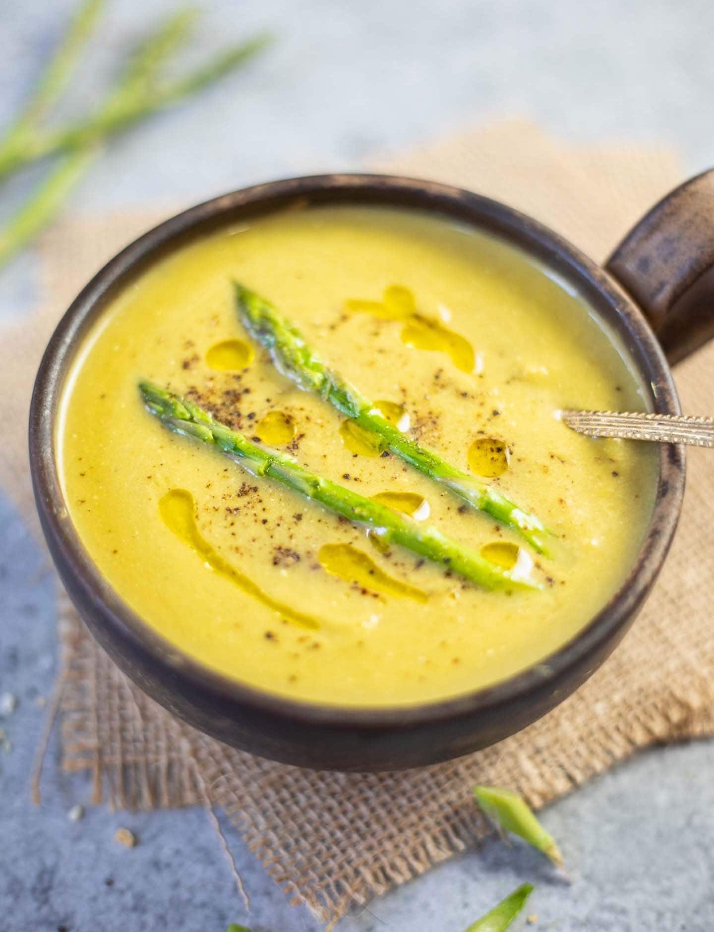 Homemade Instant Pot Asparagus Soup on a wooden bowl with olive oil on top