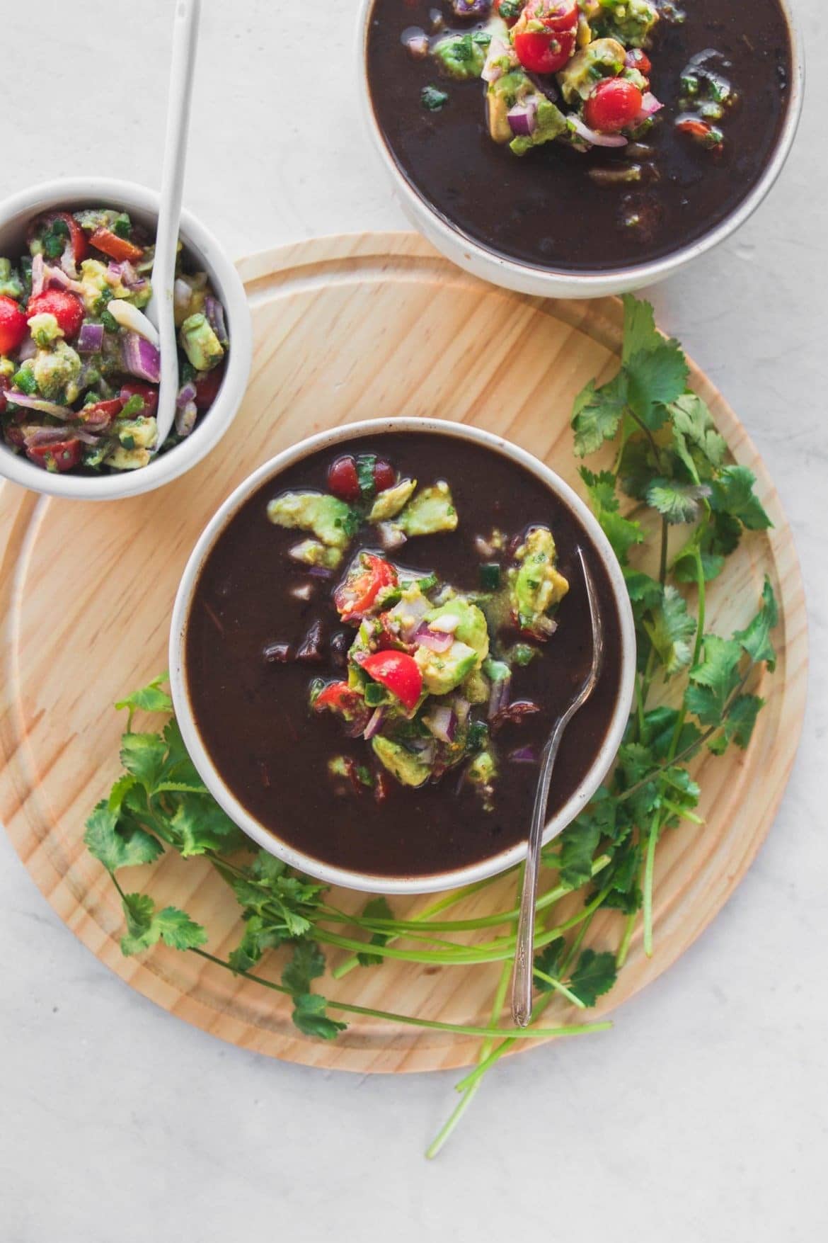 Bowls of homemade Instant Pot Black Bean Soup with avocado salsa on top