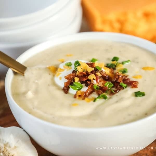 Bowl of homemade Instant Pot Cauliflower Soup with crumbled bacon, chopped chives, cheddar cheese and sour cream on top