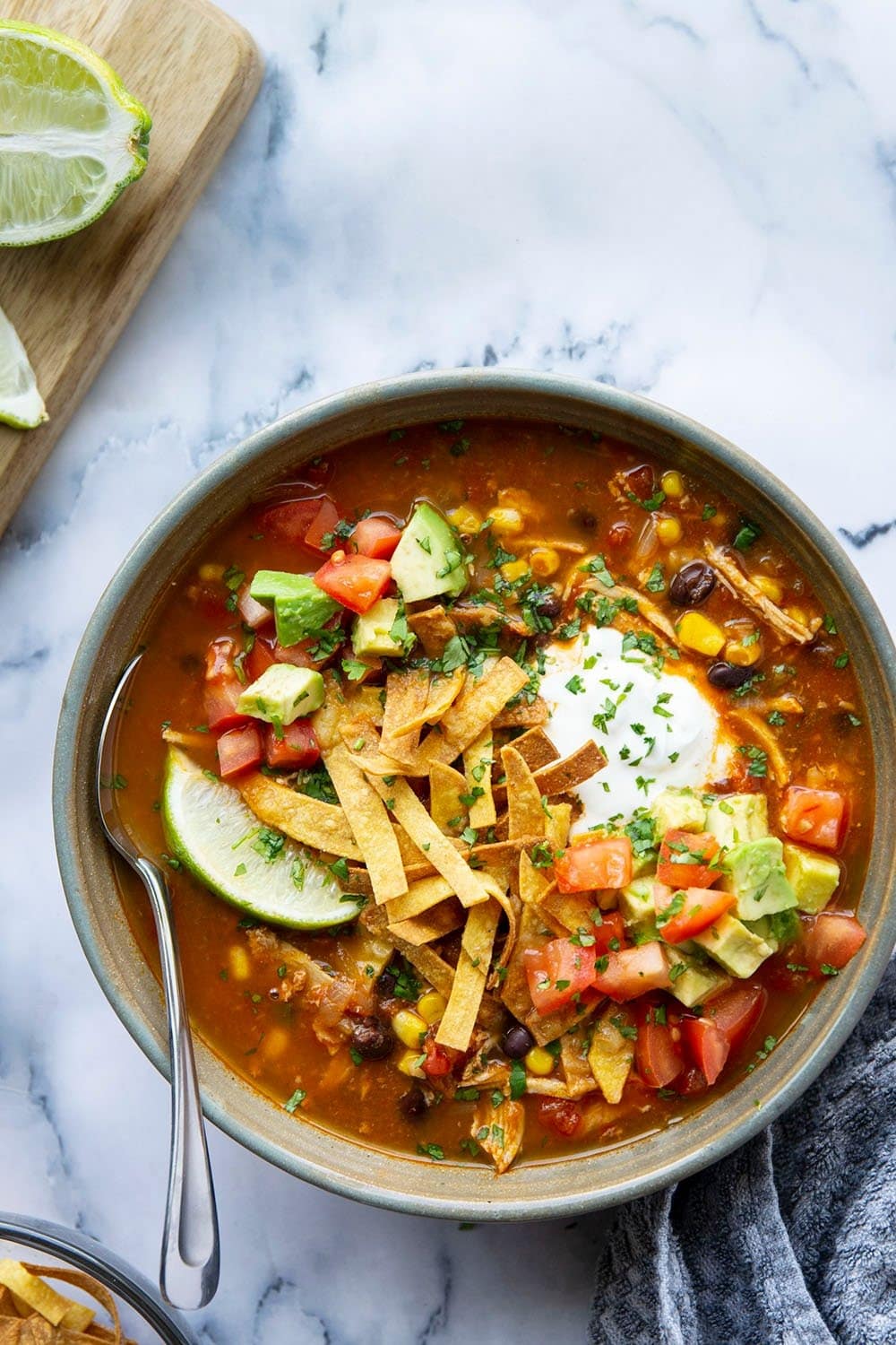 Bowl of homemade Instant Pot Chicken Tortilla Soup with petite-diced tomatoes, sweet corn, black beans, diced avocado and sour cream