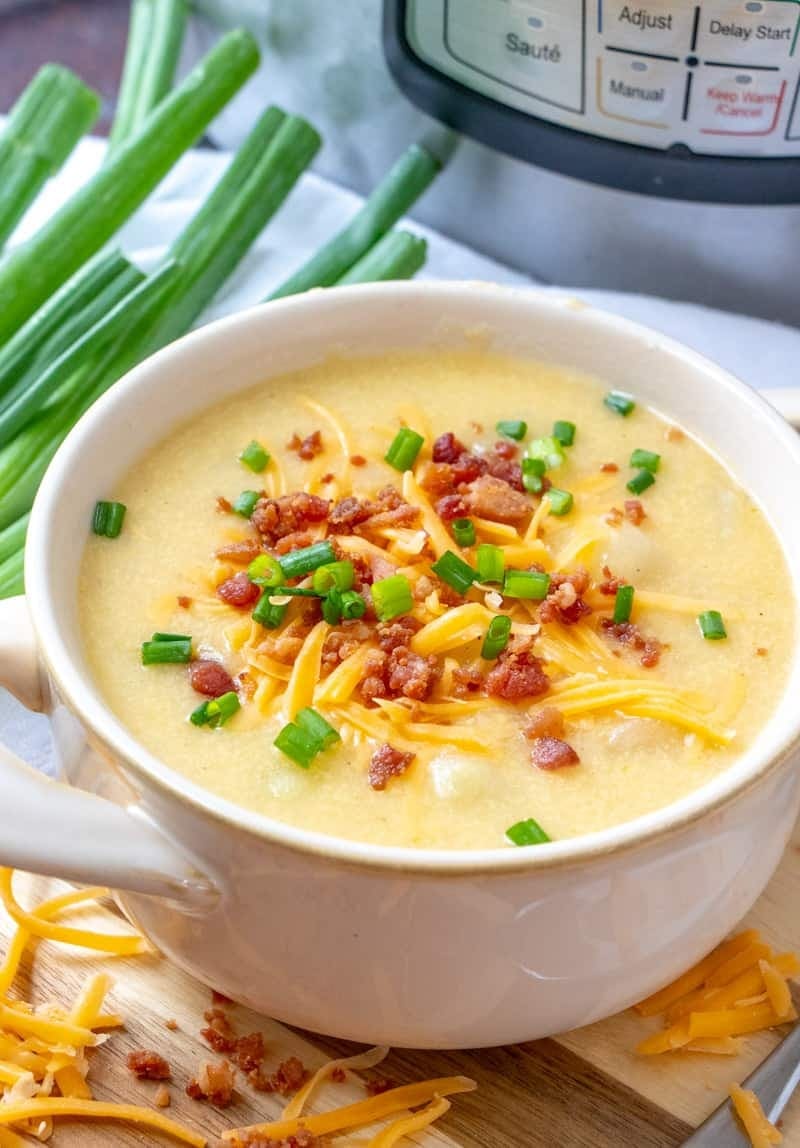 Bowl of homemade Instant Pot Potato Soup with cheddar cheese and garnished with green onions