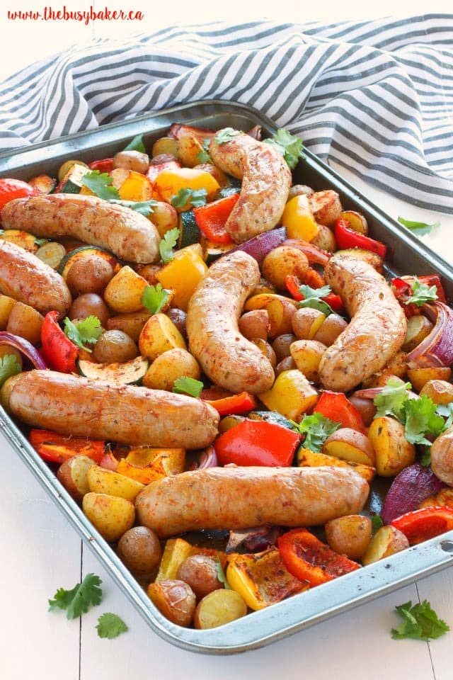 Sheet pan with roasted juicy sausages, tender baby potatoes, sweet bell peppers, zucchini, and red onions. 