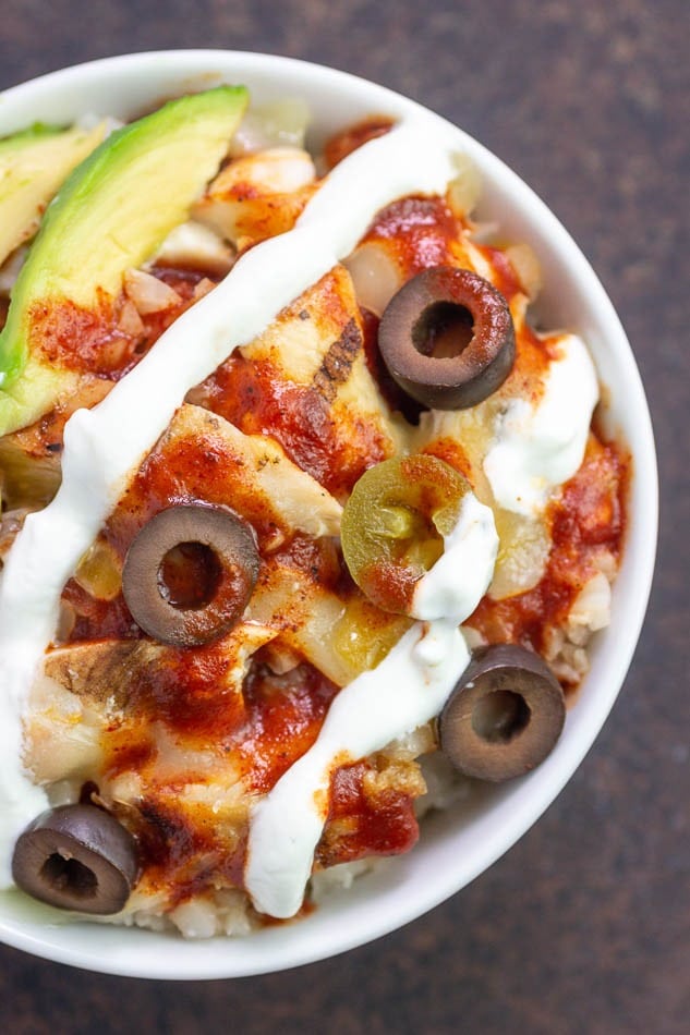 Chicken enchilada in a bowl drizzled with white cream. 