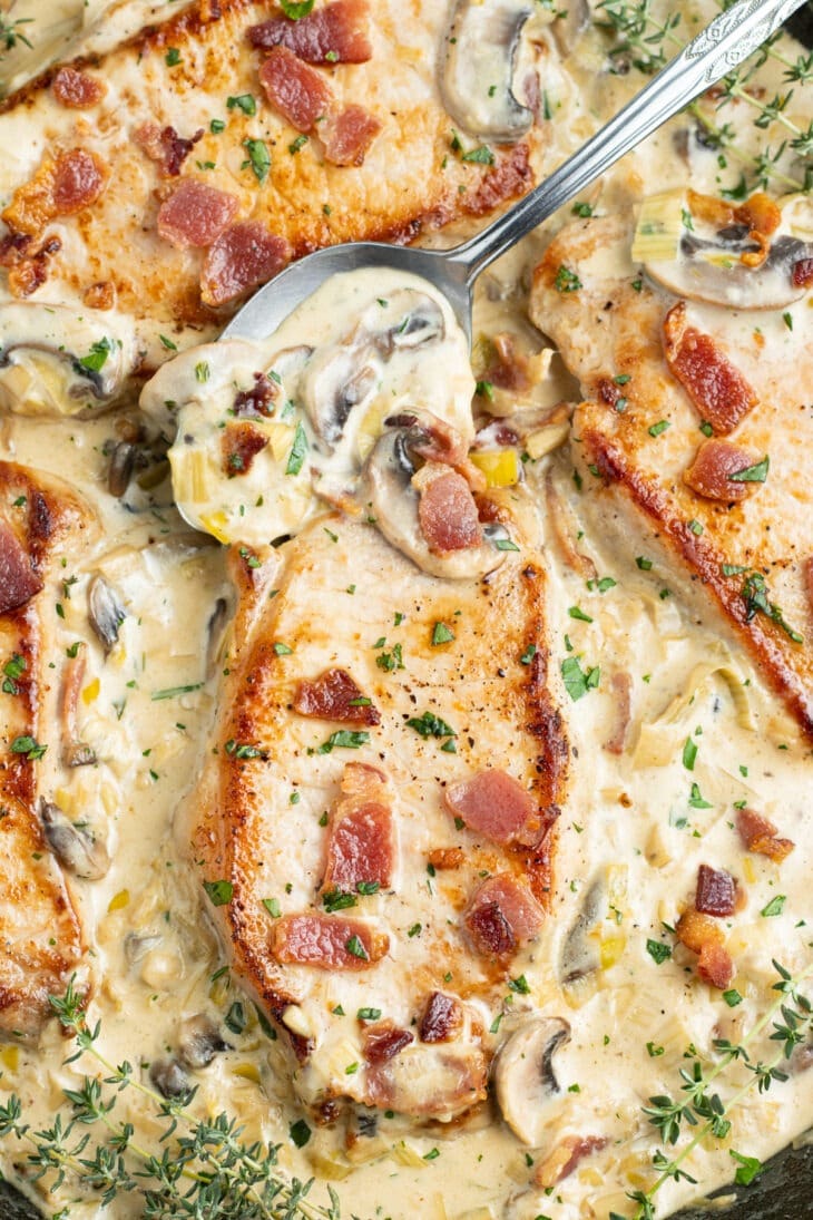 Smothered pork chops with creamy mushroom garlic sauce topped with bacon. 