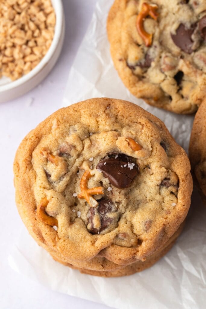 Kitchen sink cookies with chocolate chips, nuts and pretzels laid on top of parchment paper