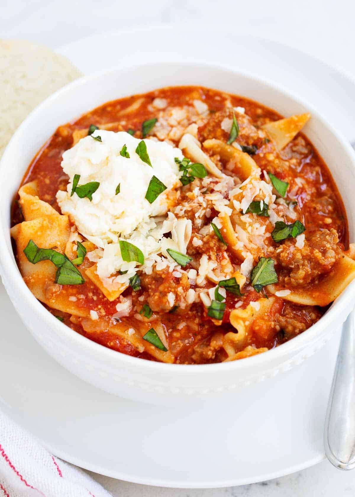 Bowl of lasagna soup with Italian sausage, bite-sized lasagna noodles, and lots of cheese in a tomato-based broth.