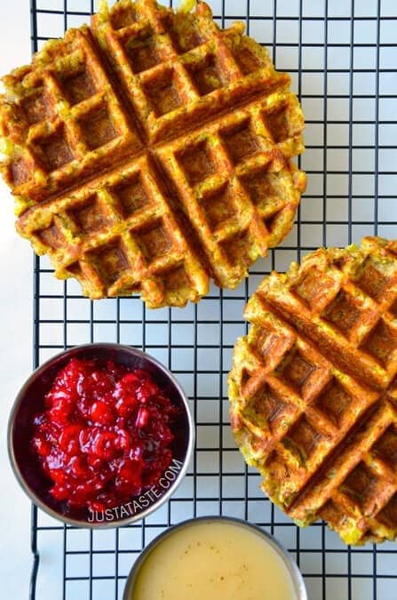 Waffles with cranberry sauce and syrup resting on a cooling rack.