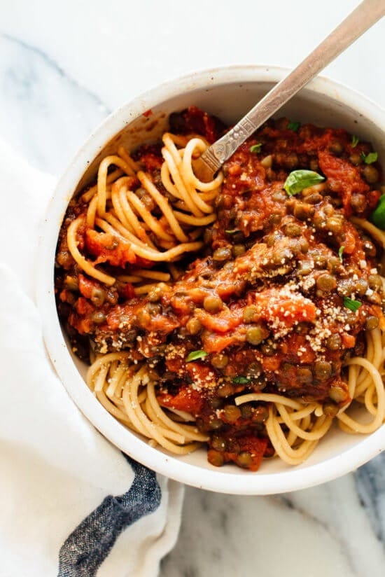 Spaghetti with lentils and marinara sauce in a bowl with fork. 