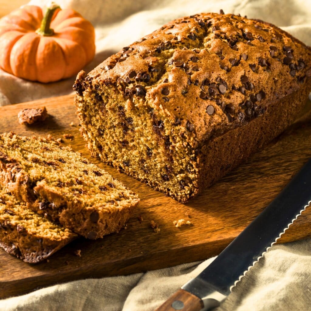 Loaf of Chocolate Chip Pumpkin Bread on a wooden cutting board.