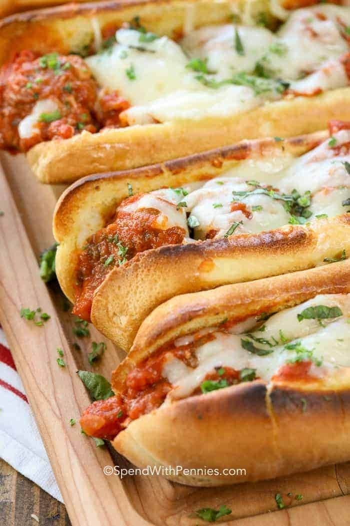Meatballs subs sandwich made with juicy meatballs, sauce marinara, and melty cheese served on a wooden tray. 