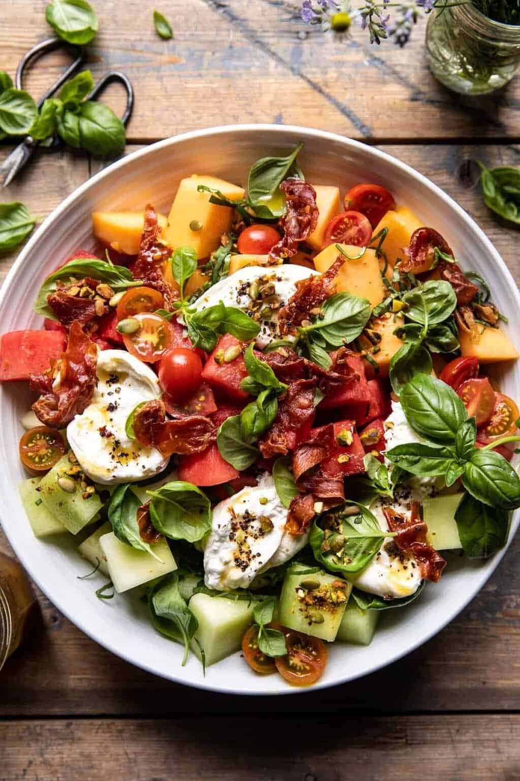 Melon Basil Burrata Salad with melon, fresh basil, cheese, prosciutto, tomatoes, and salted nuts