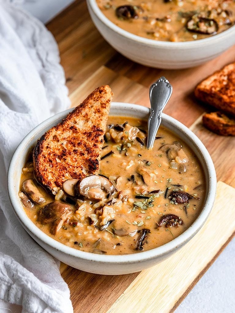 Toasted bread dipped on a bowl of homemade Mushroom Wild Rice Soup