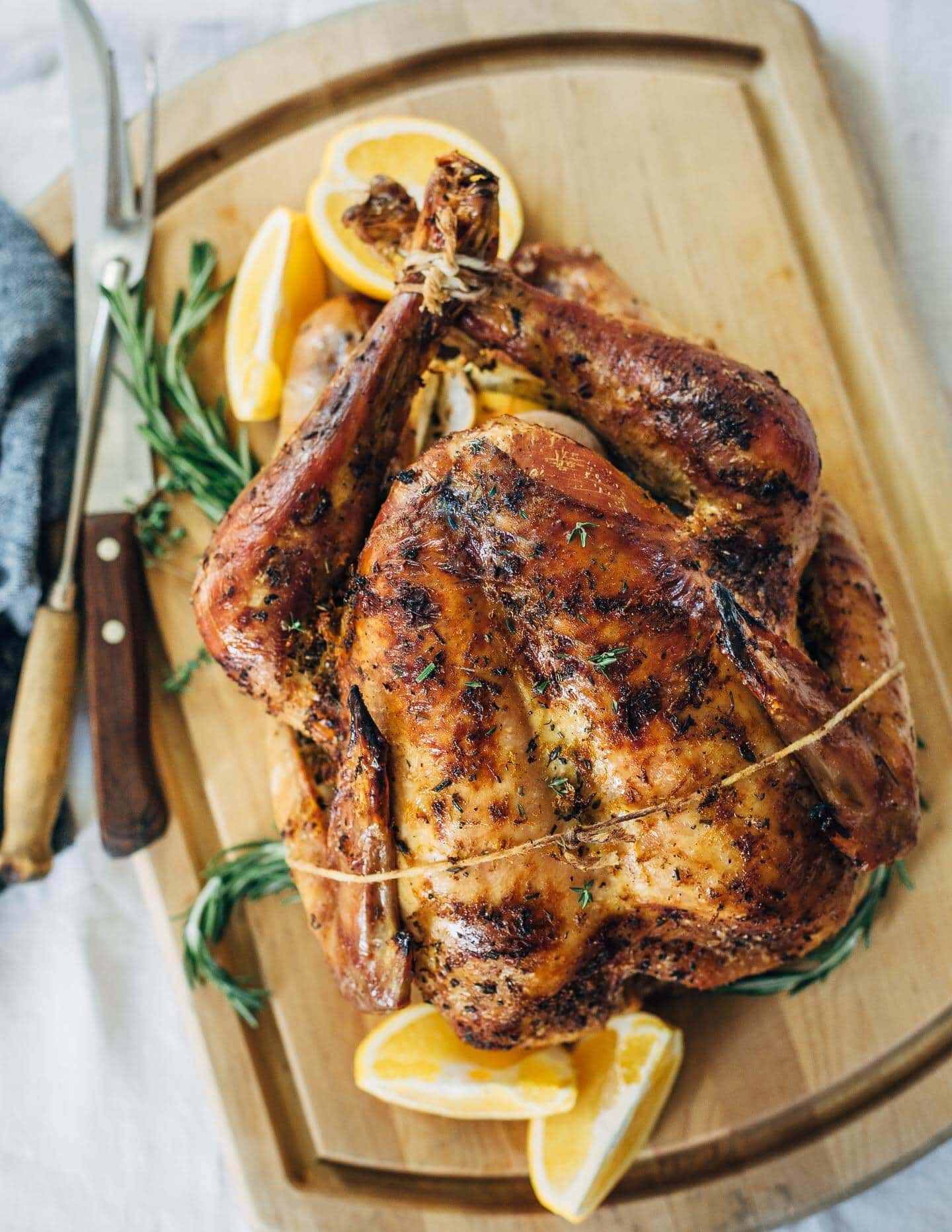 Orange and Rosemary Roasted Turkey  with slice lemon and fresh rosemary on a wooden board