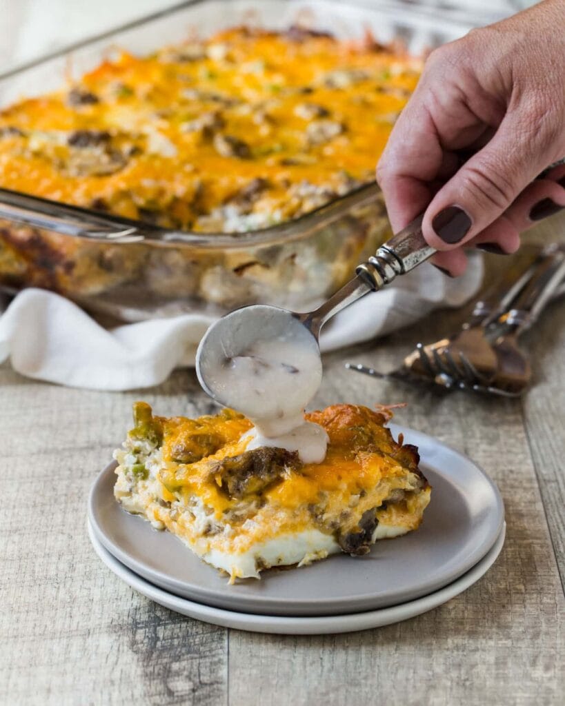 A slice of overnight fireman's breakfast casserole with sausage drizzled with mushroom sauce.