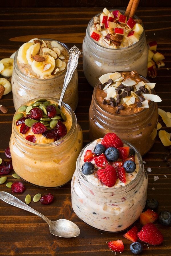 Different variants of overnight oats on mason jars topped with berries. 
