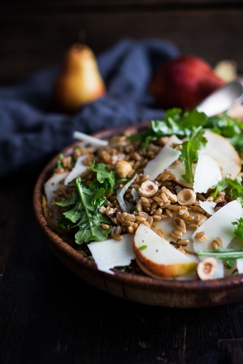 Toasted farro salad with pear, hazelnuts and arugula in a wooden bowl. 