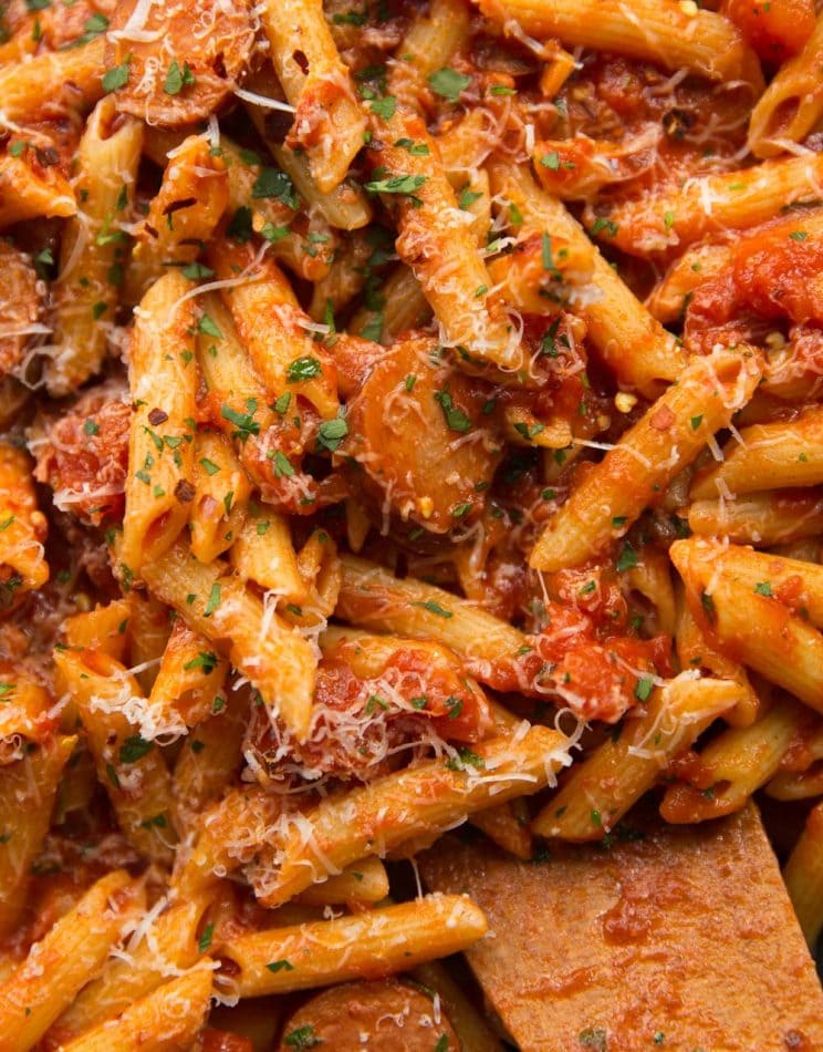 A close-up of penne pasta with sausage and tomato sauce