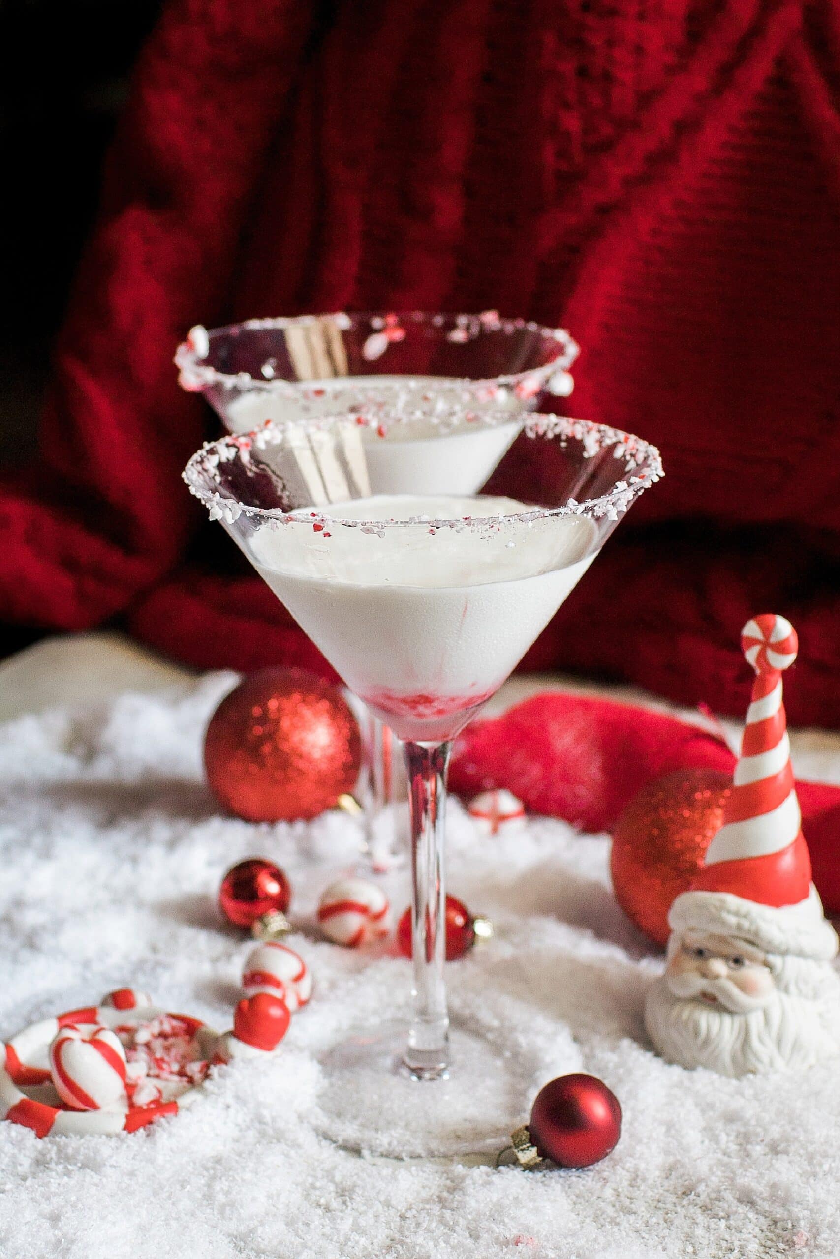 Two festive martinis with candy canes and red and white decorations.