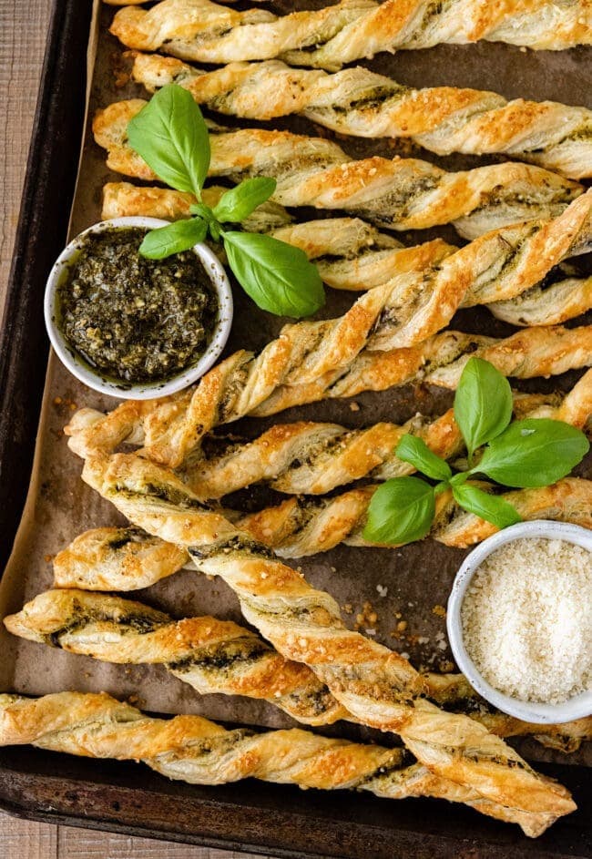 Puff pastry made with basil pesto and covered in grated parmesan cheese baked on a sheet pan.