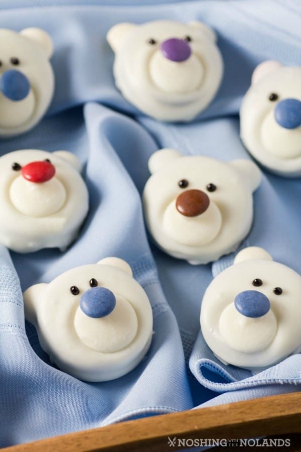 Polar bear shaped white cookies laid on blue cloth on a wooden basket. 