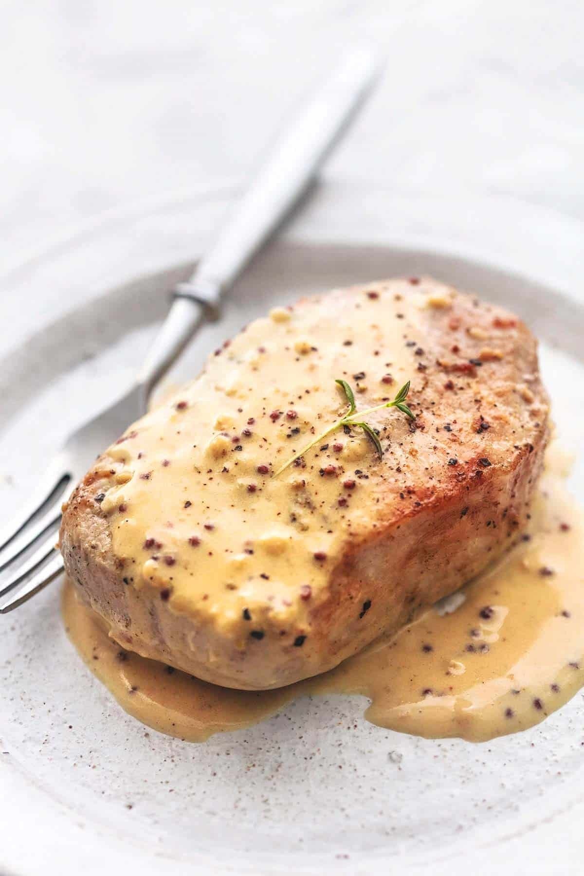 Baked pork chops with Dijon cream served on a plate. 